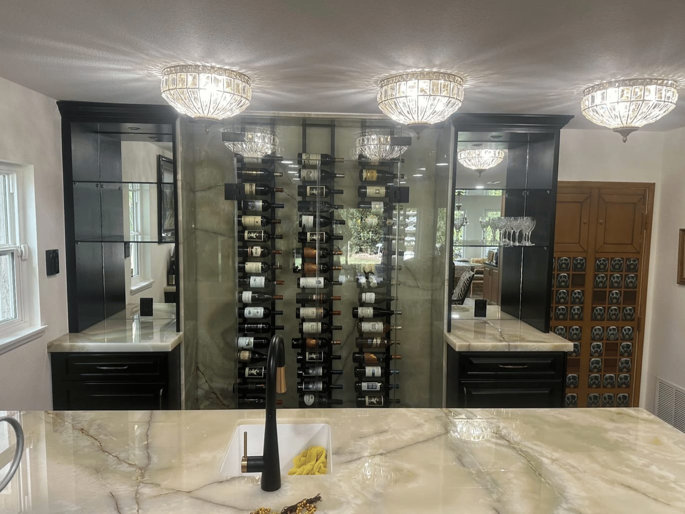 Custom kitchen with dark millwork, stone counters, and a glass wine wall